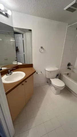a bathroom with a granite countertop sink a toilet and a mirror
