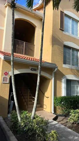 a view of white house with a small yard and plants
