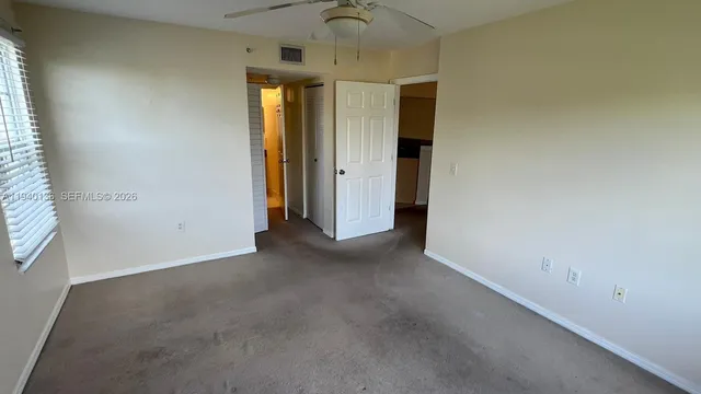a view of a room with a ceiling fan and window