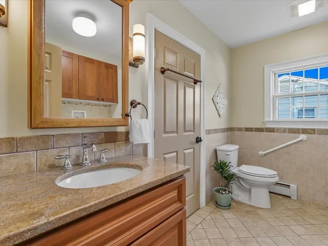 a bathroom with a granite countertop sink a toilet and a mirror