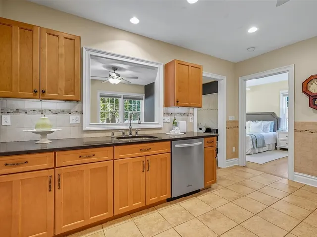 a large kitchen with kitchen island granite countertop a sink and white cabinets