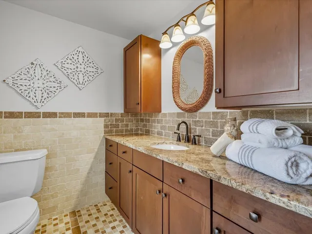 a bathroom with a granite countertop toilet sink and mirror