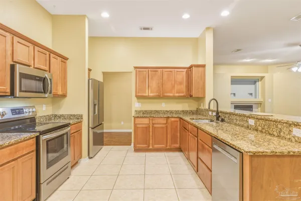 a large kitchen with stainless steel appliances granite countertop a sink stove and refrigerator