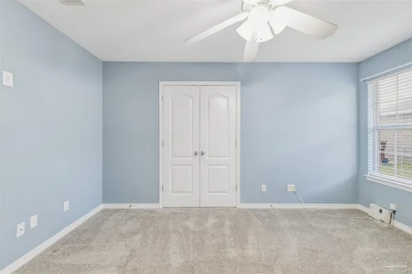 an empty room with windows and fan