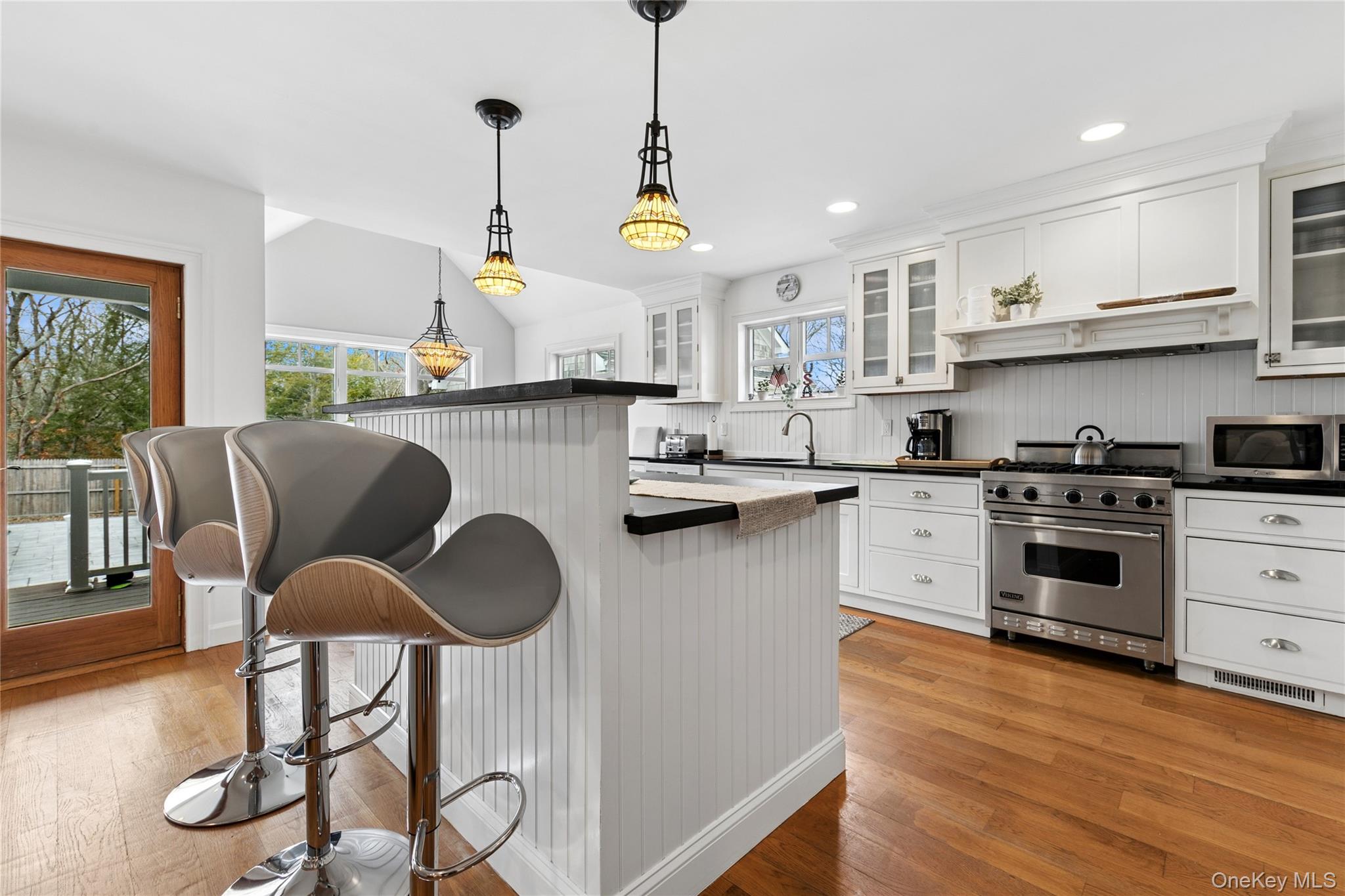 10 Foxboro Road East Quogue, NY 11946 - Photo 13 of 31 a kitchen with stainless steel appliances granite countertop a stove a sink dishwasher a dining table and chairs with wooden floor