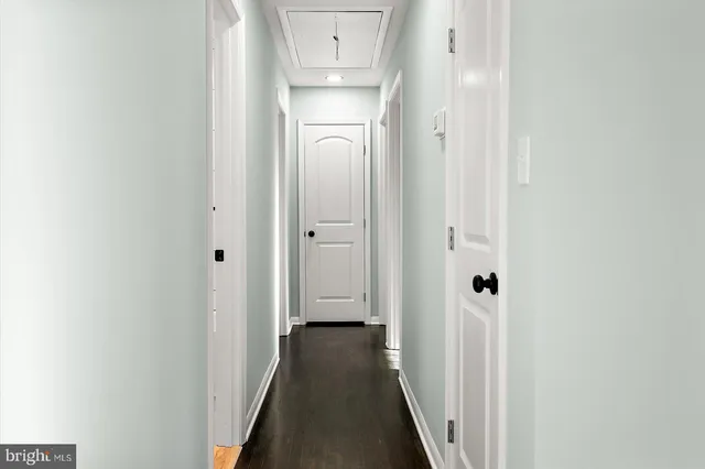 a view of a hallway with wooden floor and a door