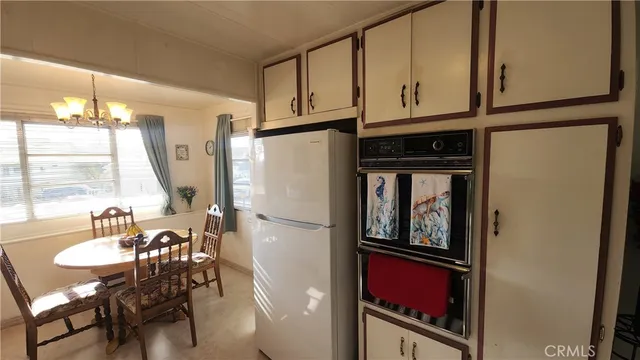 a kitchen with stainless steel appliances granite countertop a refrigerator a stove and a dining table with wooden floor