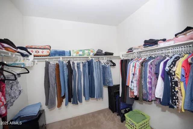 a view of walk in closet with clothes and shoes