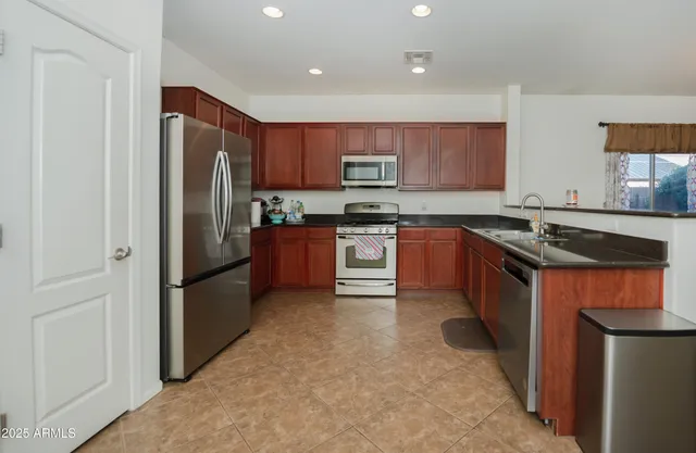 a kitchen with stainless steel appliances granite countertop a refrigerator a sink a stove a microwave and island