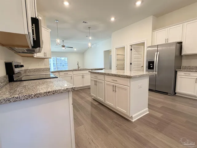 a kitchen with stainless steel appliances granite countertop a sink a stove and a refrigerator