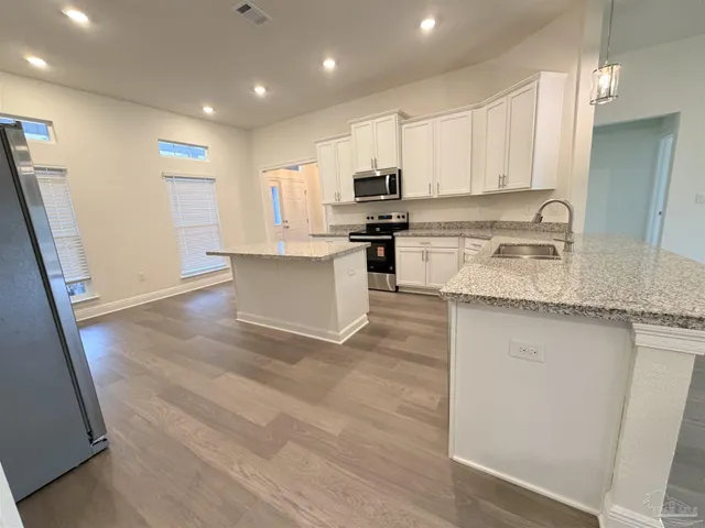a kitchen with stainless steel appliances granite countertop a refrigerator sink and white cabinets