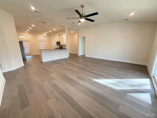a view of an empty room with wooden floor and a ceiling fan
