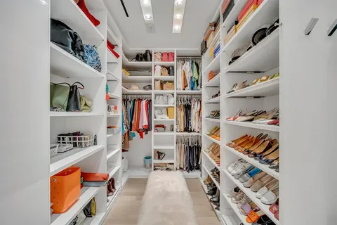 a view of walk in closet with clothes and shoes