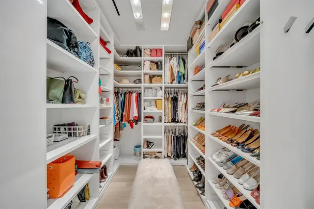 a view of walk in closet with clothes and shoes