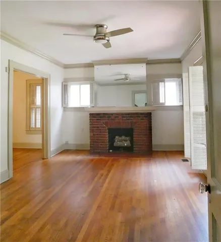 an empty room with wooden floor fireplace and windows