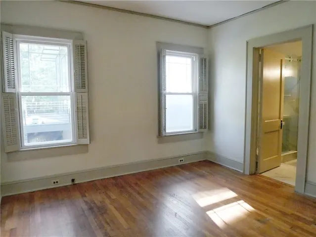 an empty room with wooden floor closet and windows