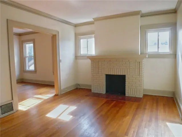 an empty room with wooden floor and a fireplace