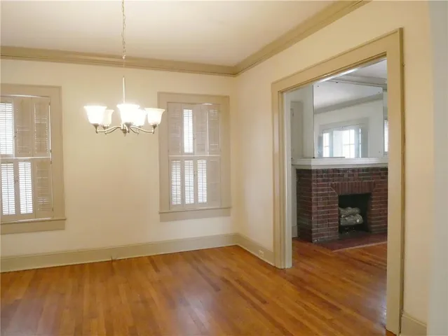 an empty room with wooden floor cabinet and windows