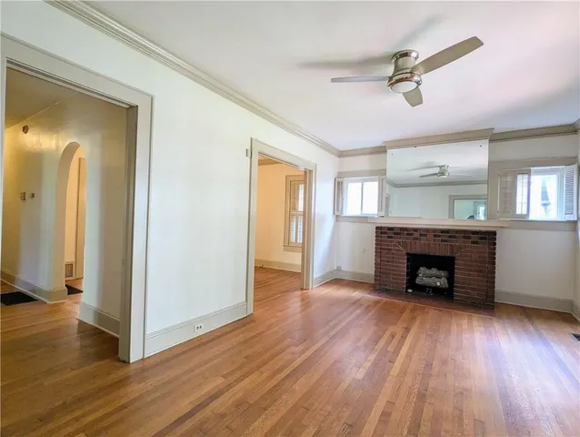 an empty room with wooden floor fireplace and windows