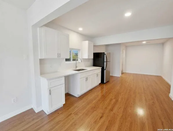 a kitchen with a sink a stove cabinets and wooden floor