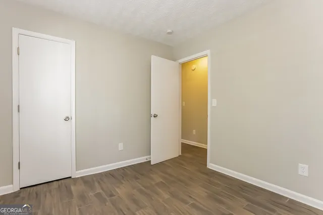 a view of an empty room with wooden floor and closet