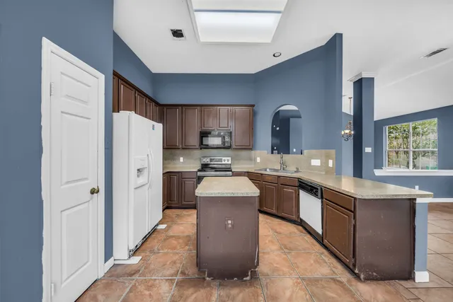 a kitchen with stainless steel appliances granite countertop a refrigerator a sink dishwasher a stove and a oven with wooden floor