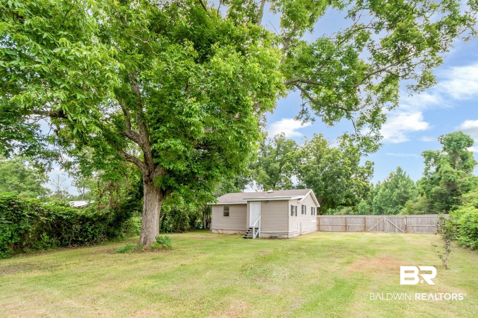 2905A McFarland Road, Unit F Mobile, AL 36695 - Photo 27 of 29 Expansive backyard featuring a manicured lawn, established mature tree, wood privacy fencing, and a detached structure with siding and a shingle roof
