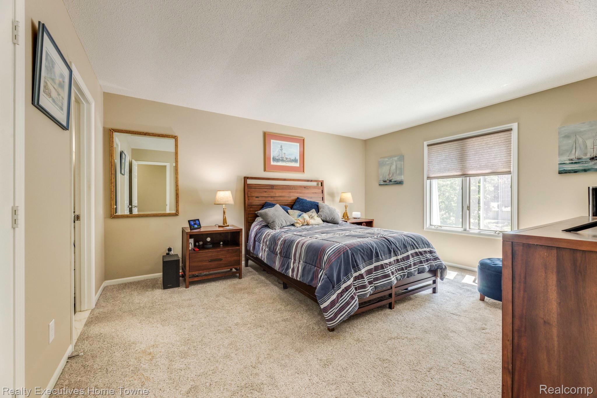 1467 Krafft Road, Unit 8 Port Huron, MI 48060 - Photo 16 of 30 Carpeted bedroom featuring a large window with blinds, a wood-finish bed frame, and neutral wall tones