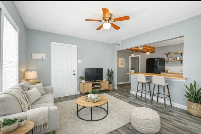 a living room with furniture kitchen view and a wooden floor