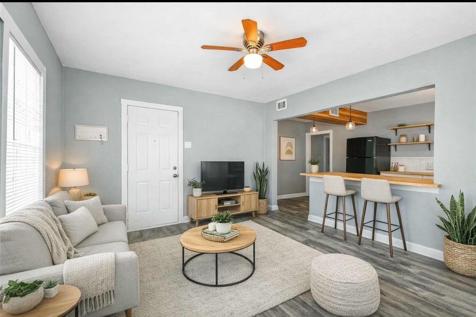 a living room with furniture kitchen view and a wooden floor