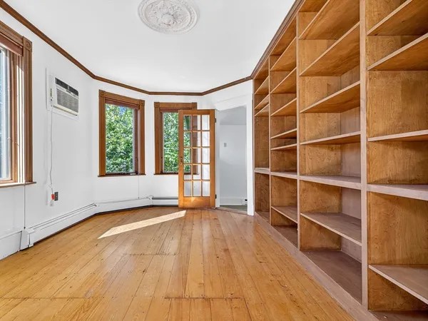 a view of an empty room with a window and wooden floor