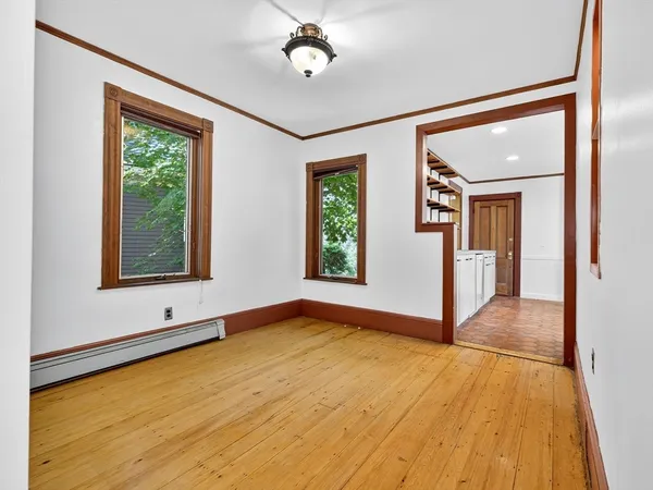 a view of an empty room with window and wooden floor