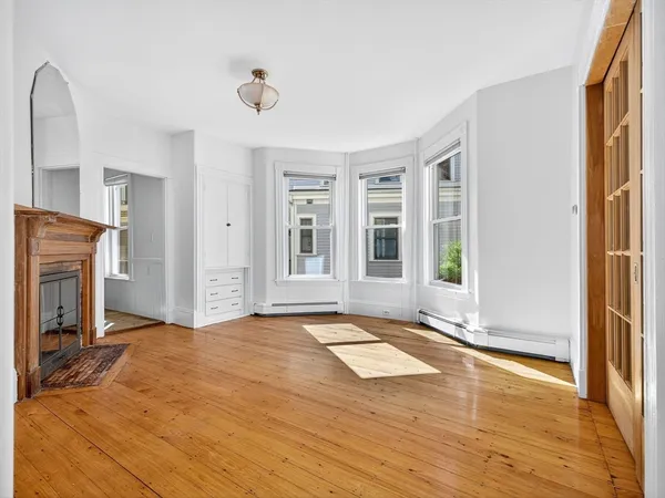 a view of an empty room with window and wooden floor