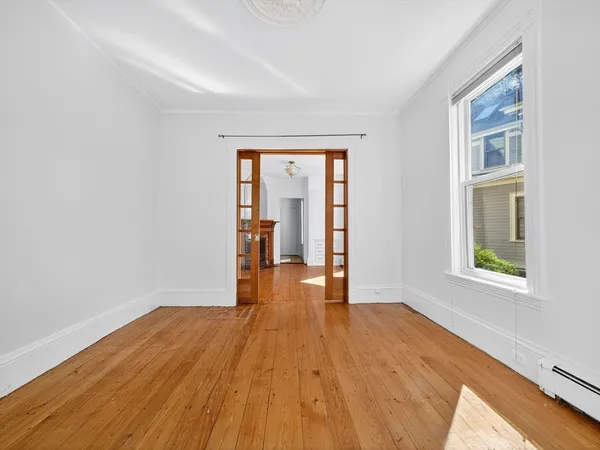 a view of an empty room with wooden floor and a window