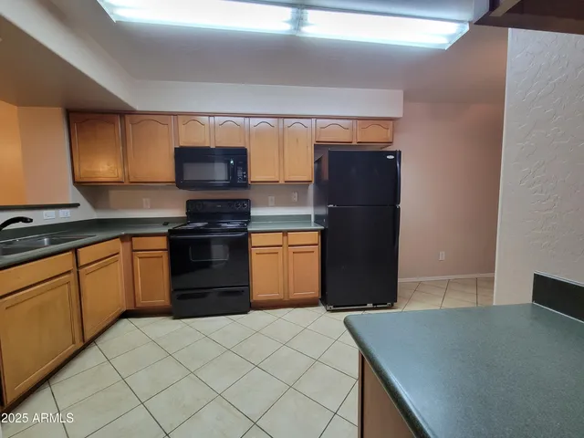 an empty room with chandelier fan and windows