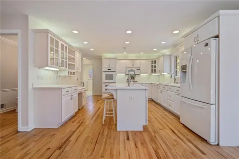 a kitchen with kitchen island wooden floors appliances and cabinets