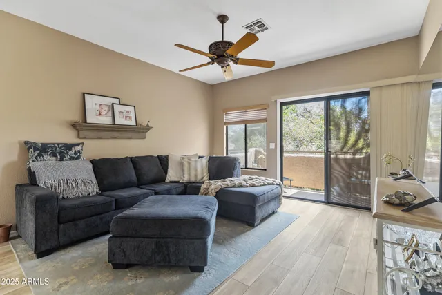 a living room with furniture a ceiling fan and a large window