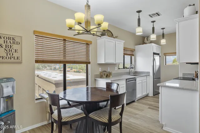 a kitchen with stainless steel appliances kitchen island granite countertop a table chairs and a refrigerator