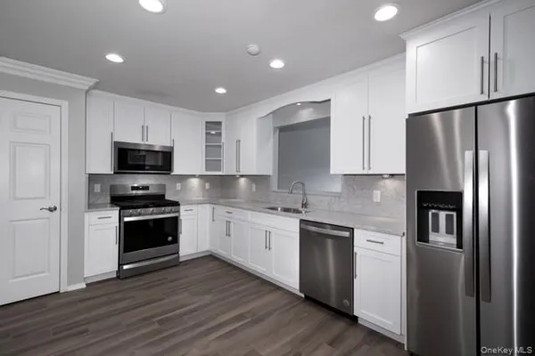 a kitchen with stainless steel appliances granite countertop a refrigerator a stove top oven a sink and dishwasher with wooden floor