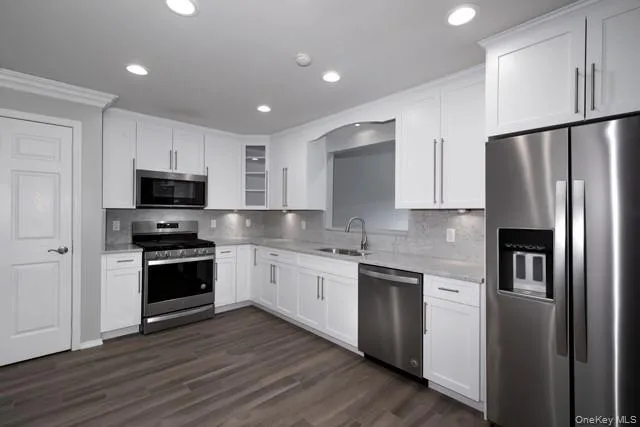 a kitchen with stainless steel appliances granite countertop a refrigerator a stove top oven a sink and dishwasher with wooden floor