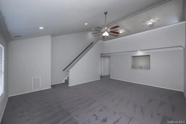 an empty room with stairs and a ceiling fan