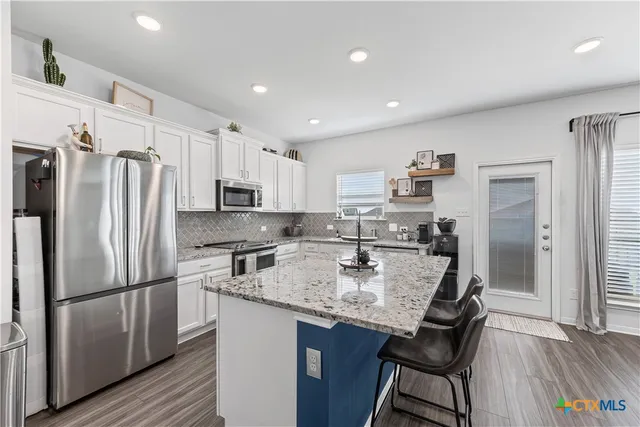 a kitchen with stainless steel appliances granite countertop a refrigerator a sink dishwasher a stove and a refrigerator with wooden floor