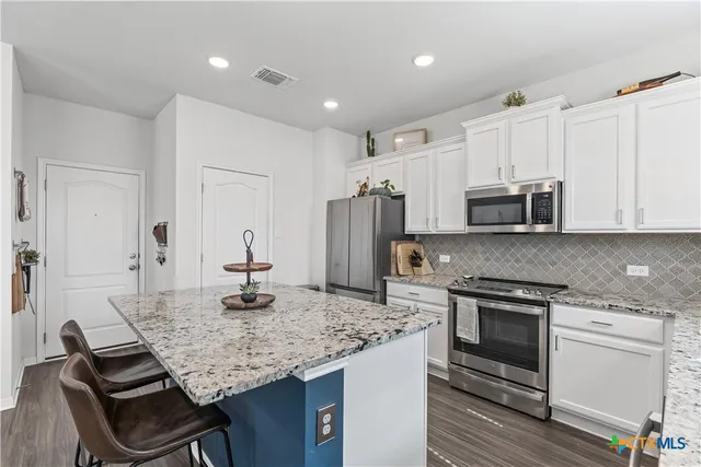 a kitchen with kitchen island granite countertop a stove and a sink