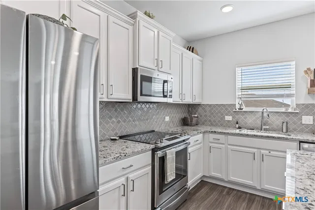 a kitchen with stainless steel appliances white cabinets and a stove top oven