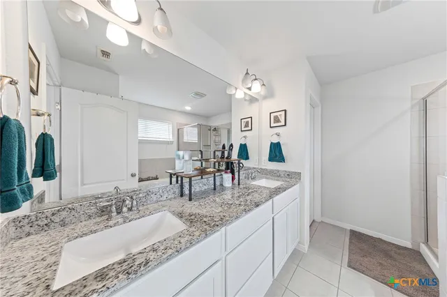 a bathroom with double vanity sinks a vanity a lamp and a mirror