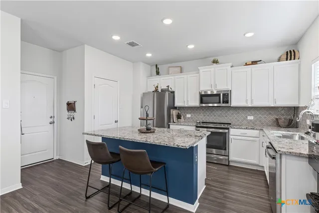 a large kitchen with stainless steel appliances granite countertop a table chairs sink and cabinets