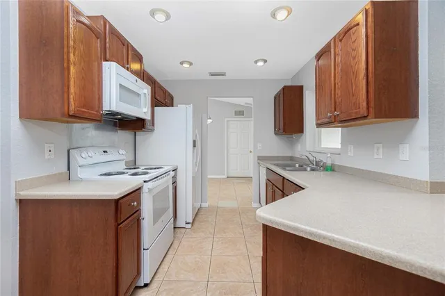 a kitchen with a sink dishwasher a stove top oven a refrigerator and cabinets