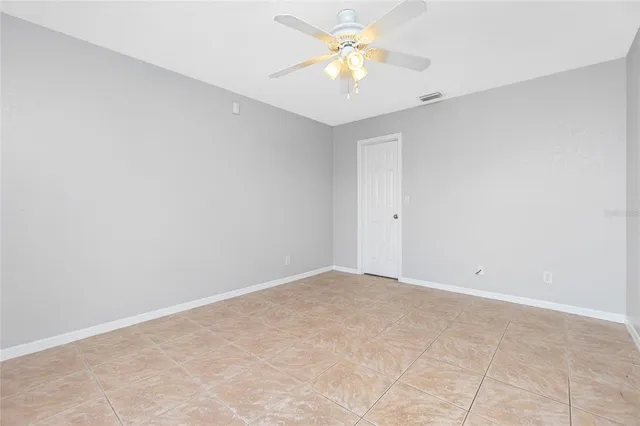 an empty room with a chandelier fan and windows