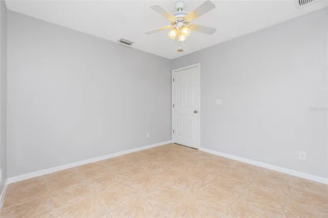 an empty room with a window and a chandelier fan