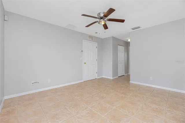 an empty room with ceiling fan and window